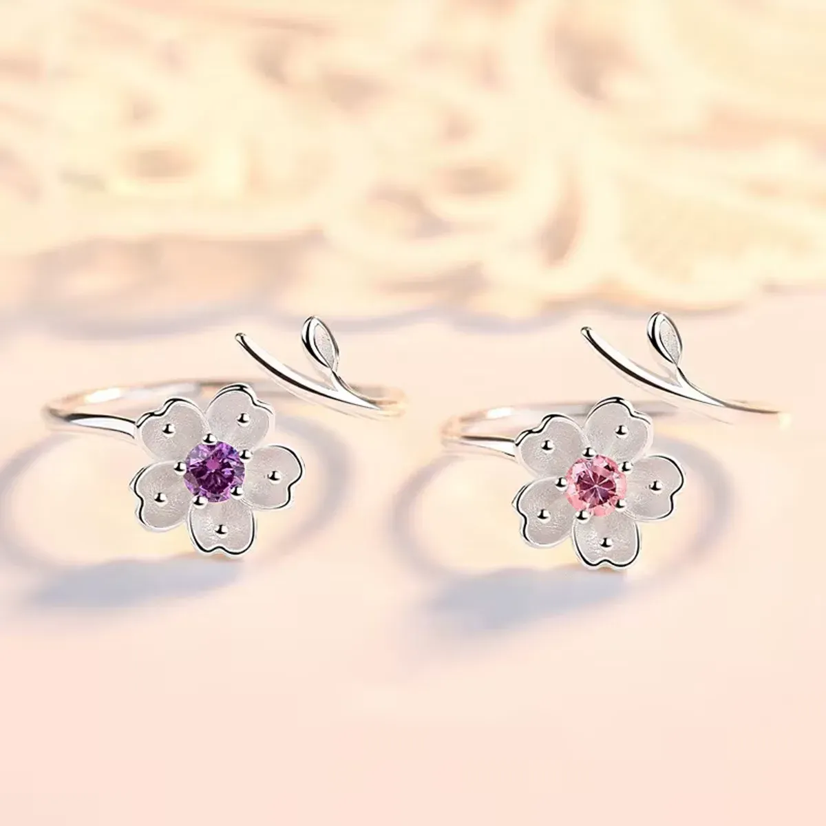 Deux bagues fleur en argent avec pierres rose et violette sur fond doux
