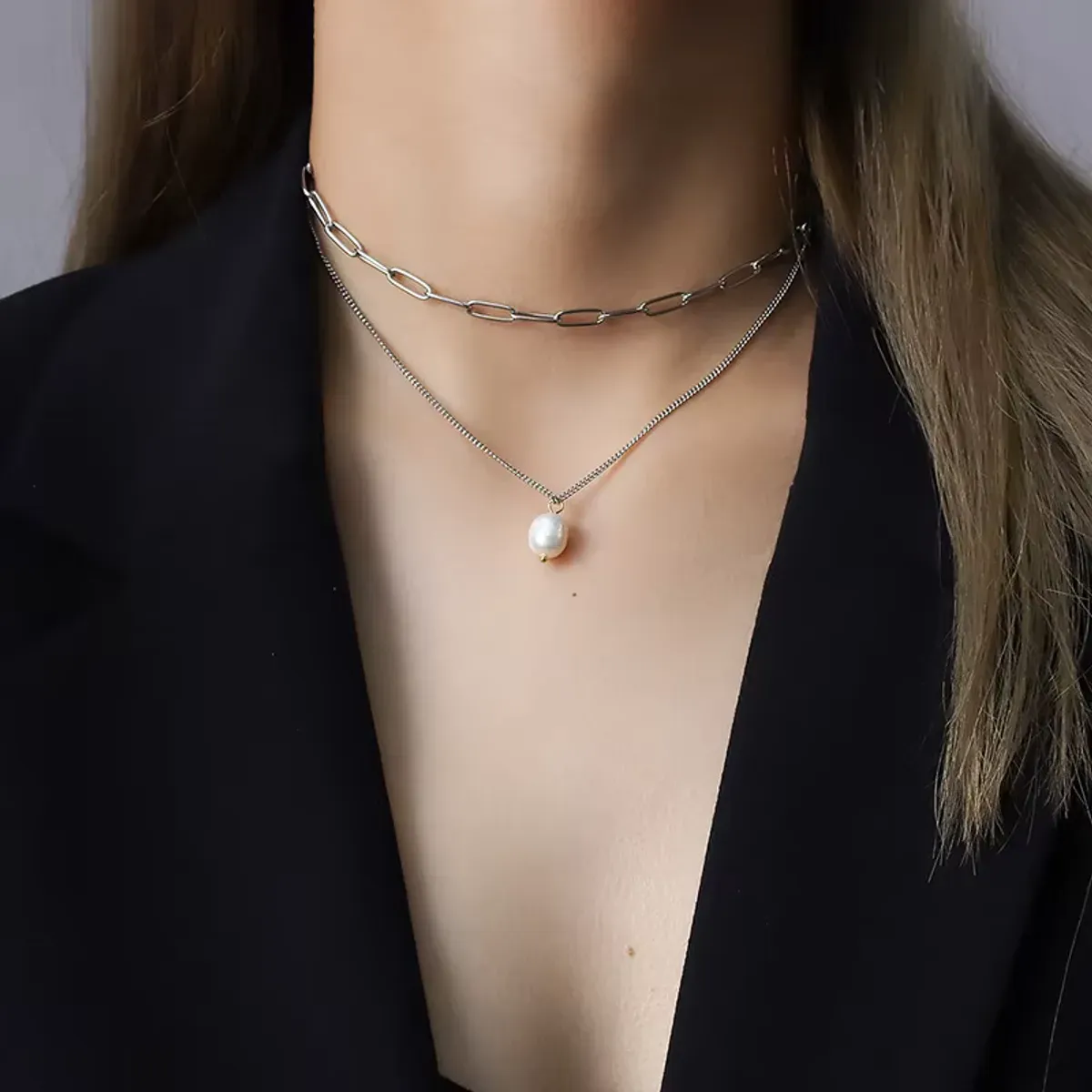 Collier double chaîne avec perle porté avec blazer noir
